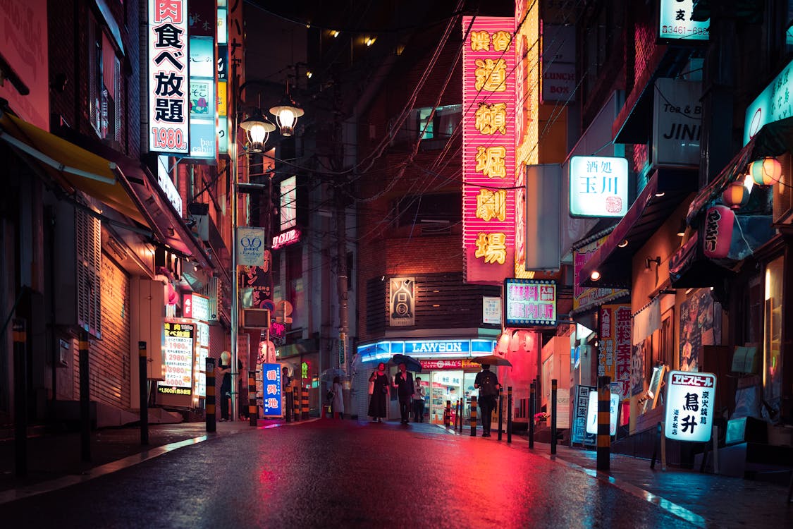 Neon-lit street in Tokyo, Japan at night with glowing signs and wet pavement reflections