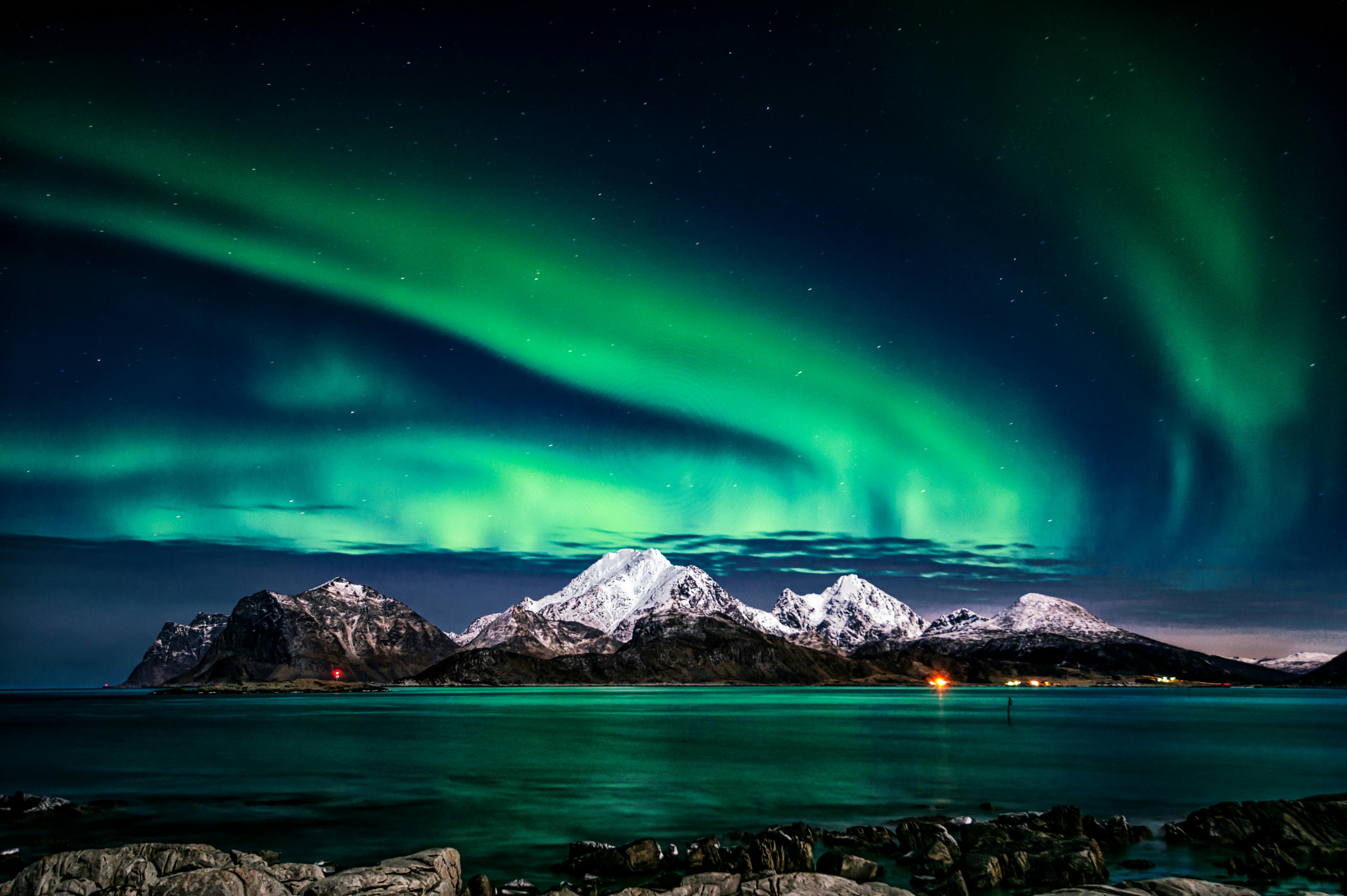 Northern lights aurora borealis dancing green and purple above a snow-covered Norwegian fjord landscape